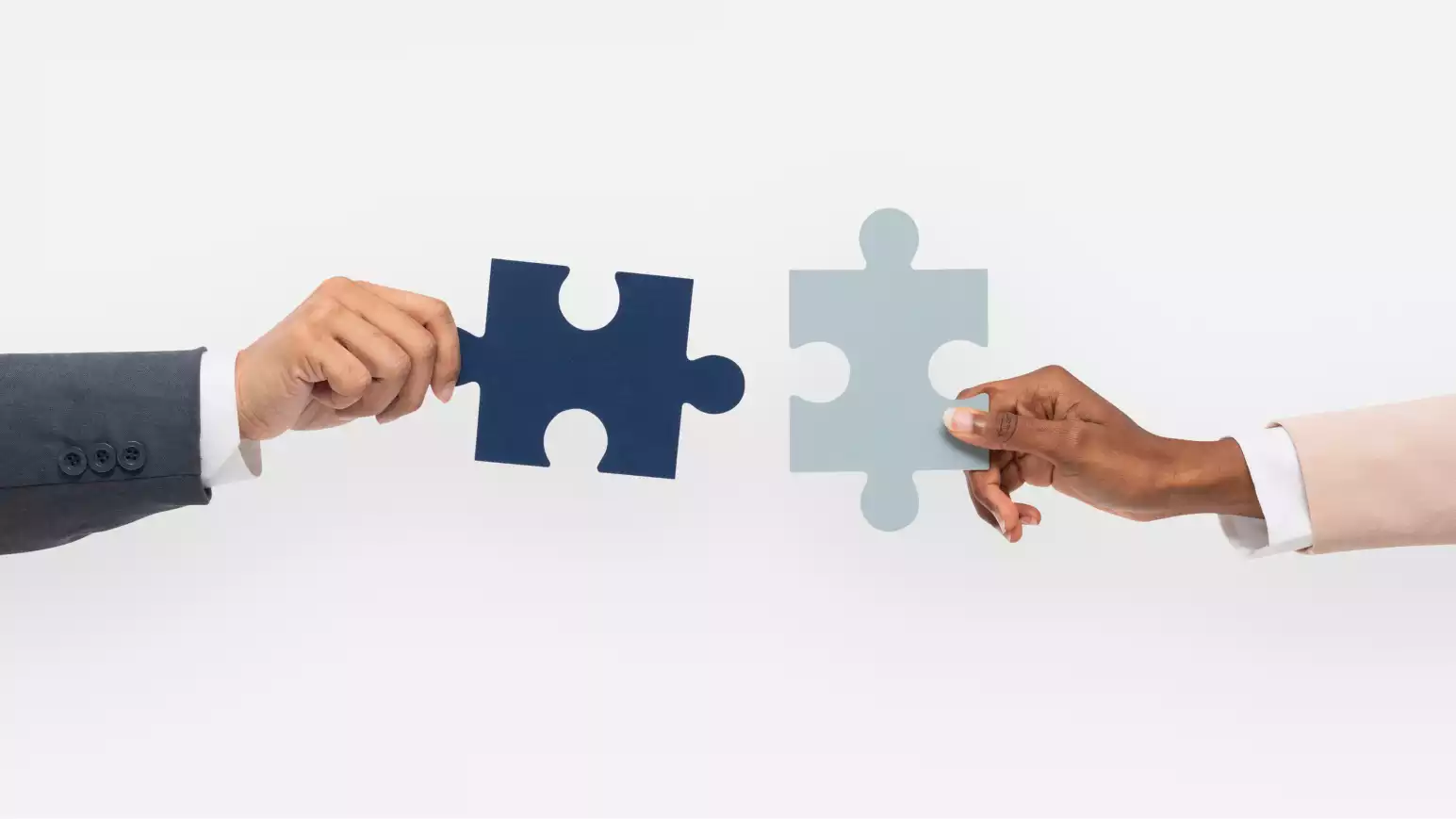 Two hands from diverse individuals holding matching puzzle pieces, poised to connect.