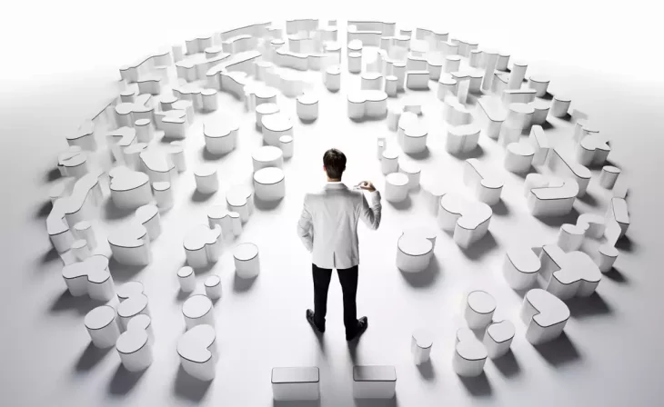 Man observing circular arrangement of white 3D puzzle pieces