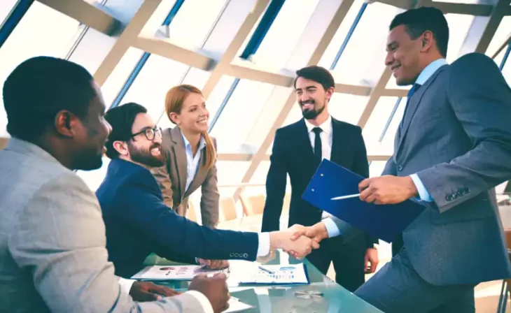 Professionals shaking hands in modern sunlit office