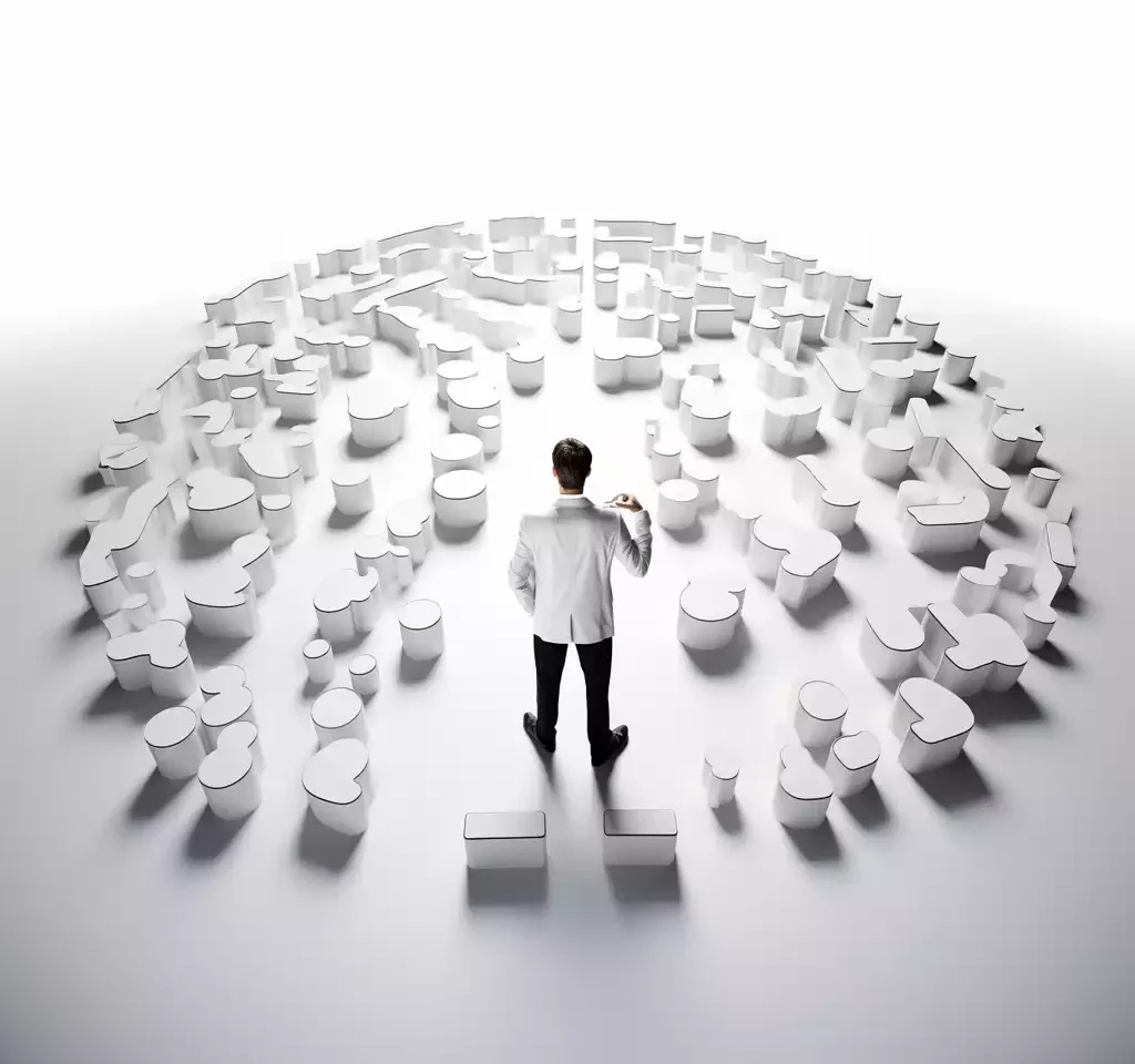 Man observing circular arrangement of white 3D puzzle pieces