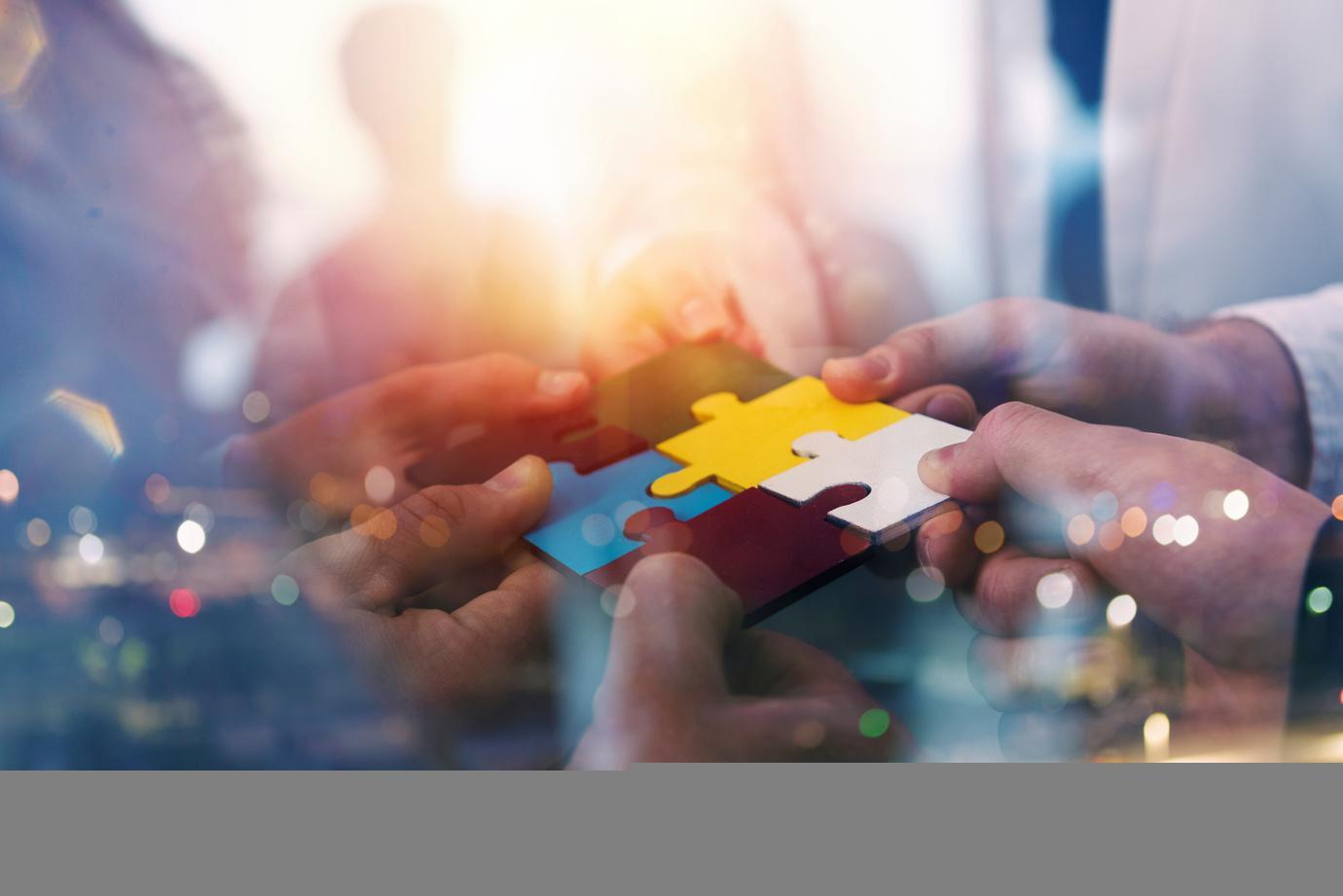 Business people connecting puzzle pieces symbolizing teamwork