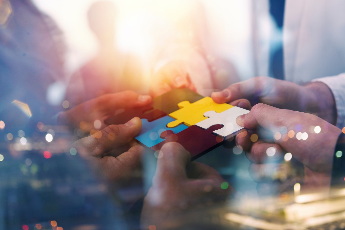 Business people join puzzle pieces in a modern office. Concept of teamwork and partnership. double exposure with light effects